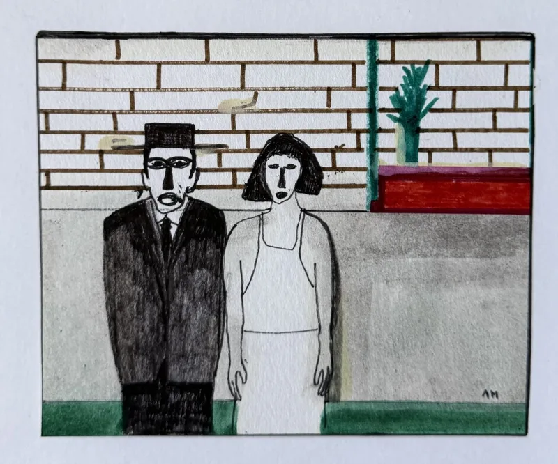Homme en costume noir et femme en robe blanche devant un mur de brique, banc rouge et plante